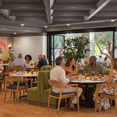 A bright restaurant dining room where people enjoy meals together around tables and sofas.