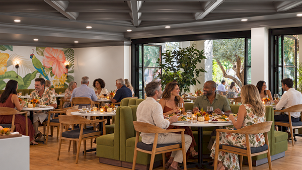 A bright restaurant dining room where people enjoy meals together around tables and sofas.